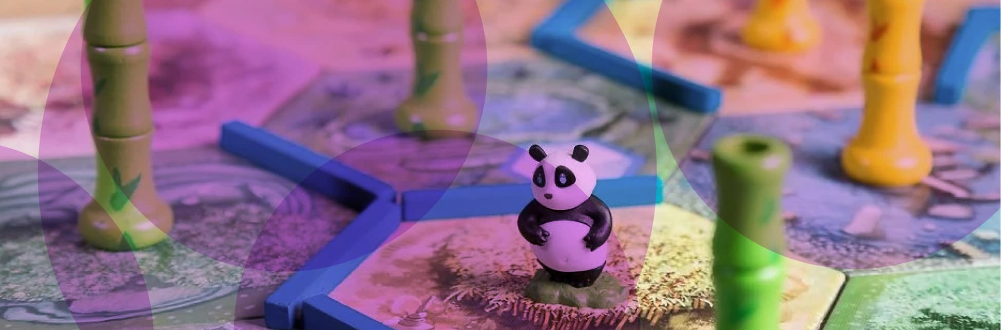 Fotografía intervenida con formas translúcidas sobre un juego de mesa; al centro hay una figura pequeña de panda y piezas azules sobre un tablero ilustrado.