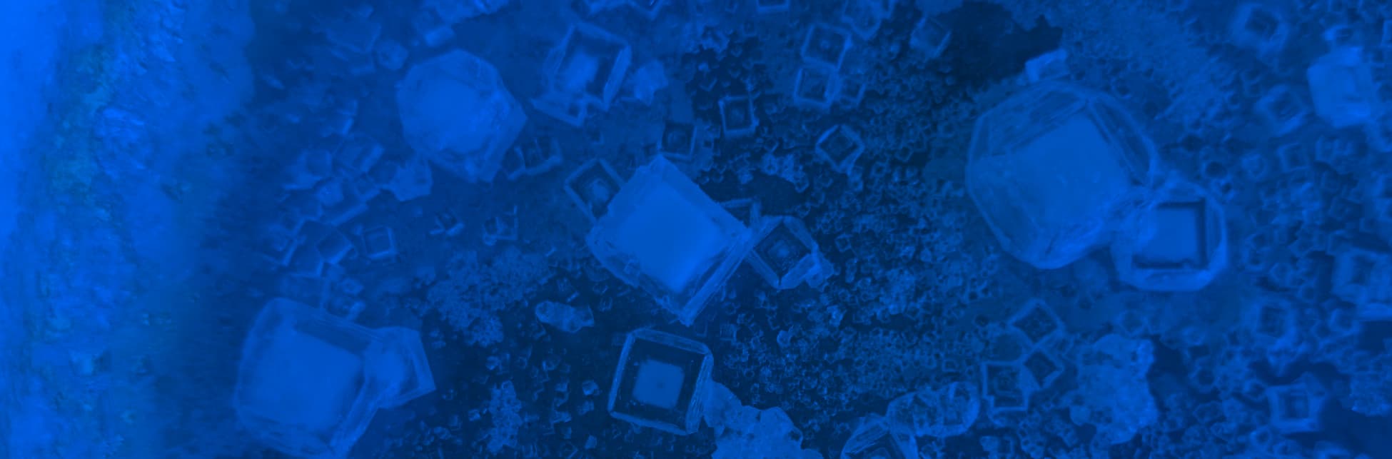 Foto de microscopio. En tonos azules aparecen cubos de diferentes tamaños por toda la imagen.