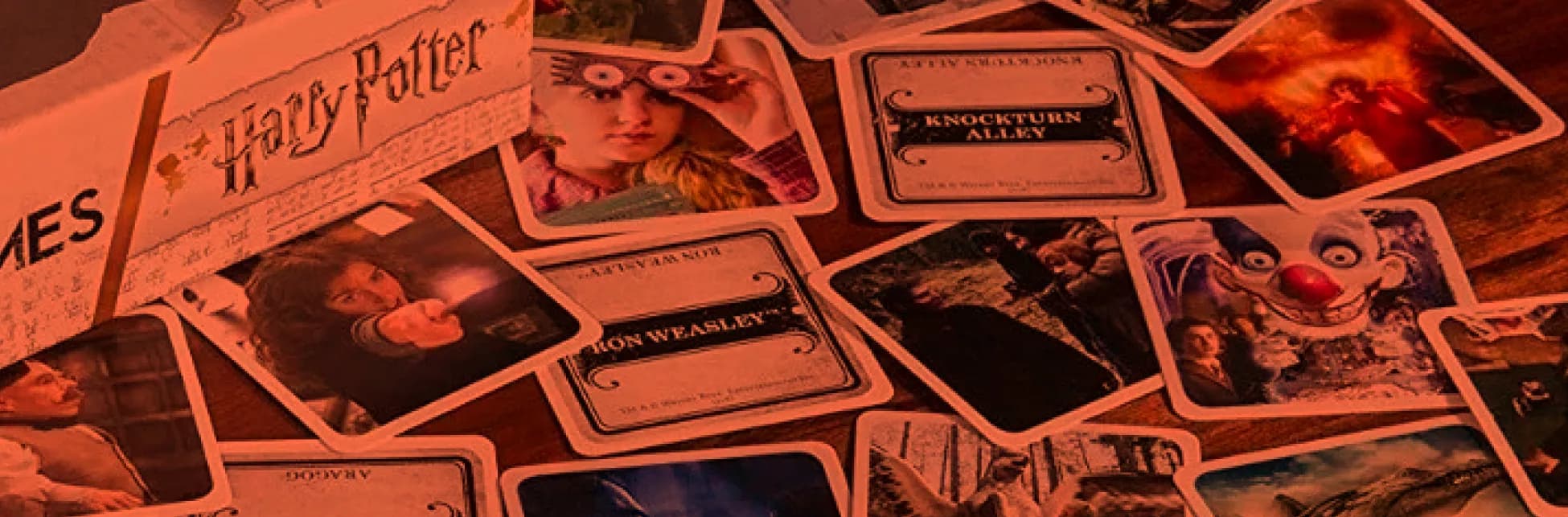 Afiche. De fondo se ven varias cartas y fichas del juego de mesa inspirado en Harry Potter, con ilustraciones y textos en inglés.