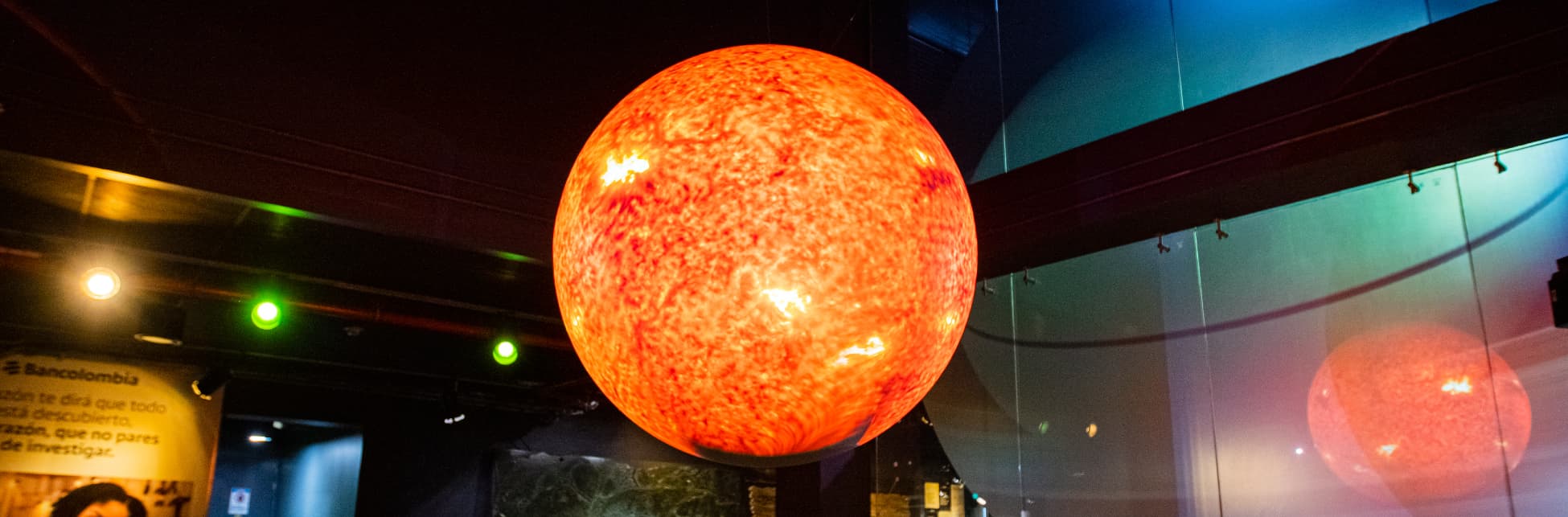 Foto. En el centro de la imagen una esfera en tonos naranjas en medio de un salón. 