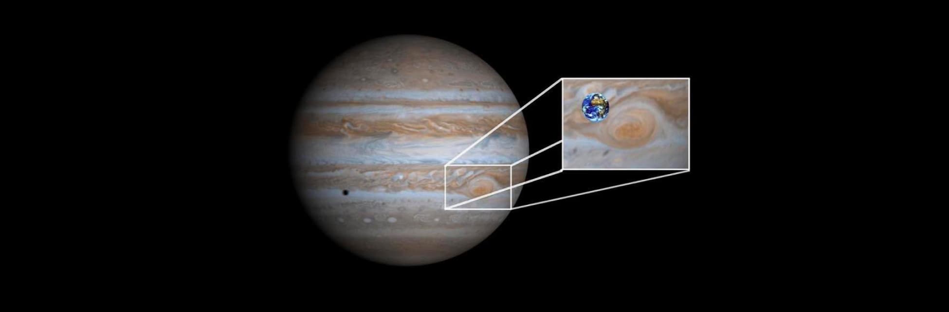 Foto. En la parte izquierda de la imagen el planeta Júpiter, una esfera con franjas cafés y grises que se alternan, Se hace un zoom al planeta y aparece en una porción muy pequeña, el planeta Tierra. 