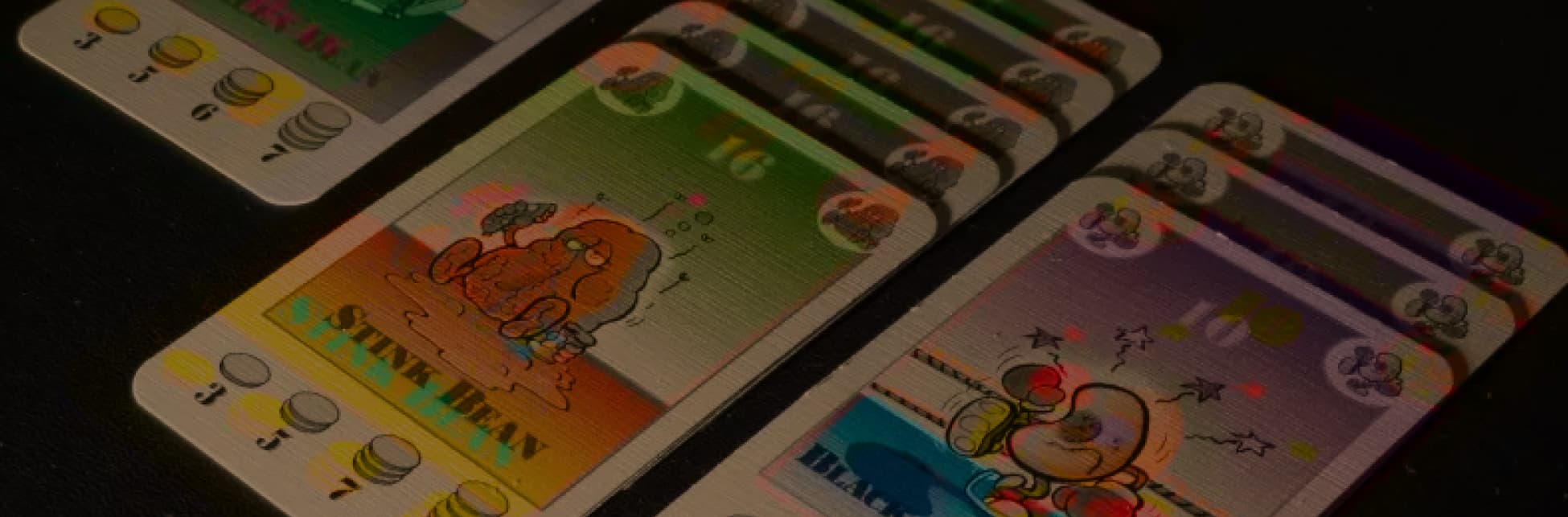 Foto. Varias cartas apiladas en filas con dibujos de fríjoles personificados.
