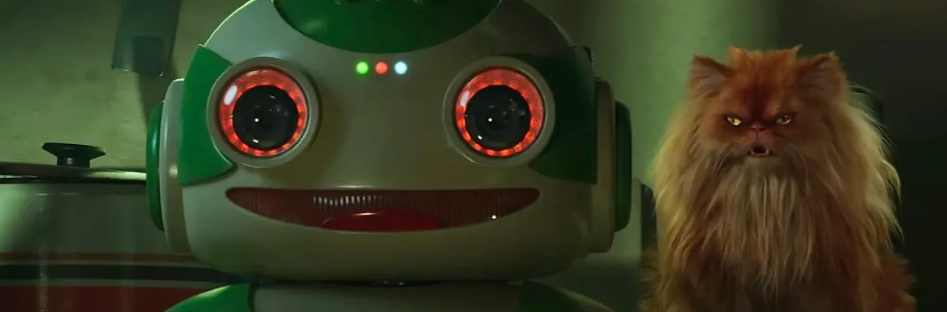 Fotograma. En el costado derecho, se observa un robot de color blanco y verde con ojos circulares iluminados en rojo, que mira hacia el frente.