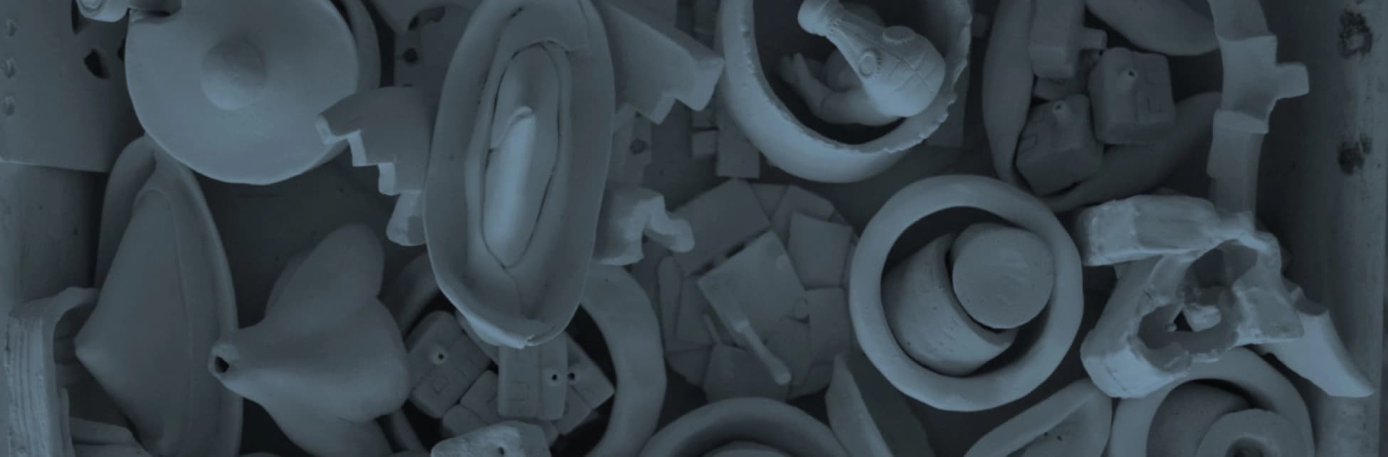 Fotografía. Sobre un fondo gris azulado, formas de cerámica apiladas.