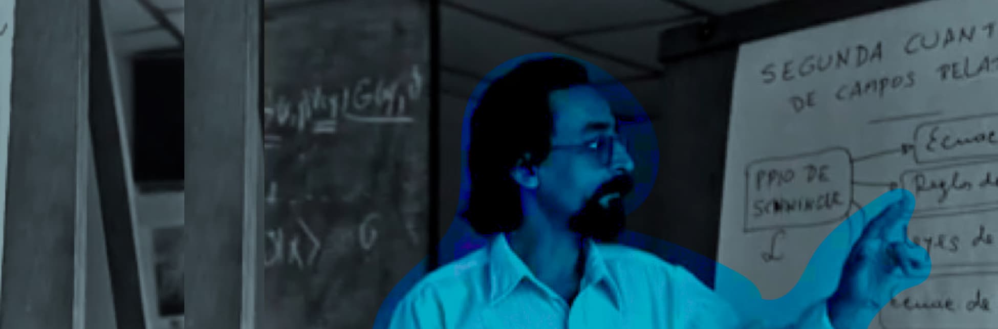 Montaje fotográfico. Un hombre de perfil, con gafas, barba y cabello largo, y una camiseta blanca, señala un tablero con fórmulas escritas. Está iluminado por una luz azul, mientras el salón y el tablero están a blanco y negro.