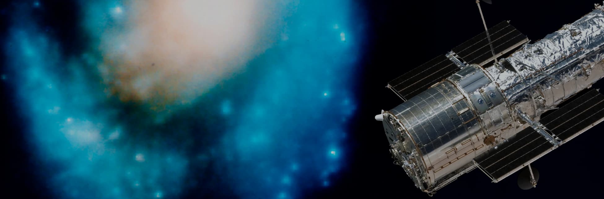 Foto. En la parte inferior de la imagen un objeto cilíndrico color plateado del que salen dos rectángulos. Al fondo se observa desenfocado un objeto celeste que parece un manchón azul con puntos blanco y un centro claro.