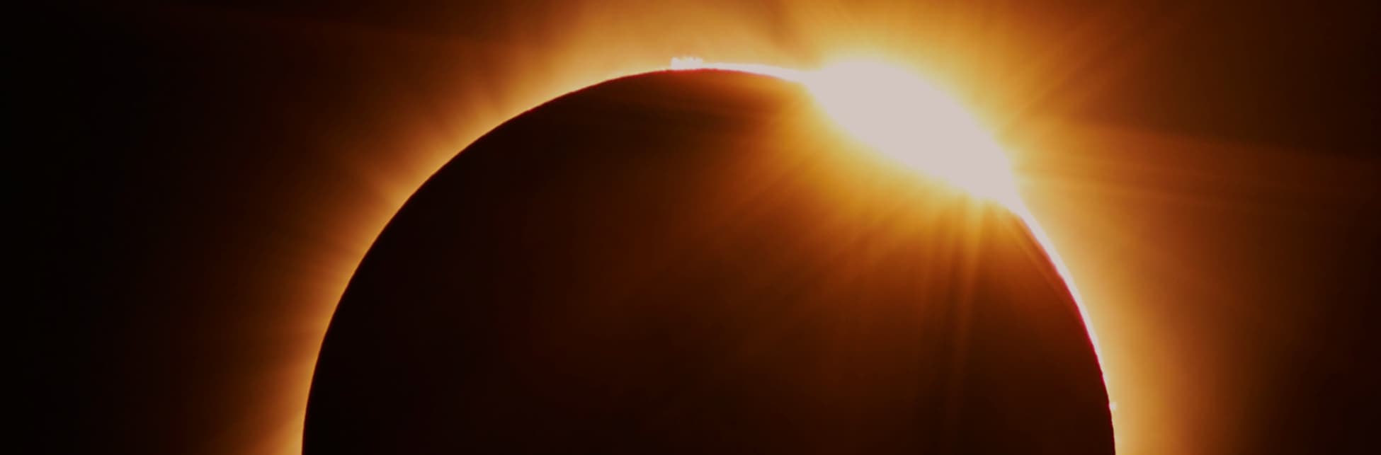 Foto. De la parte inferior de la imagen sale un medio círculo oscuro, bordeándolo hay una luz amarilla incandecente.