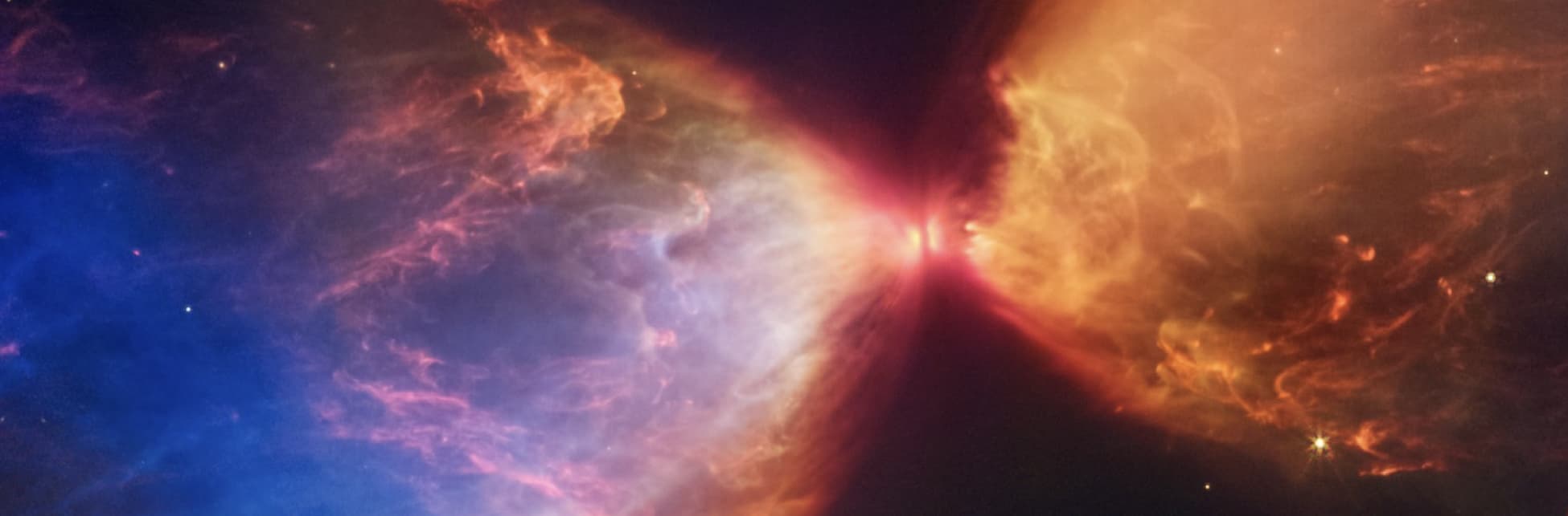Foto. En el centro de la imagen un pequeño círculo rojo que desprende hacia ambos lados un halo de luz, uno azul y otro naranjado.