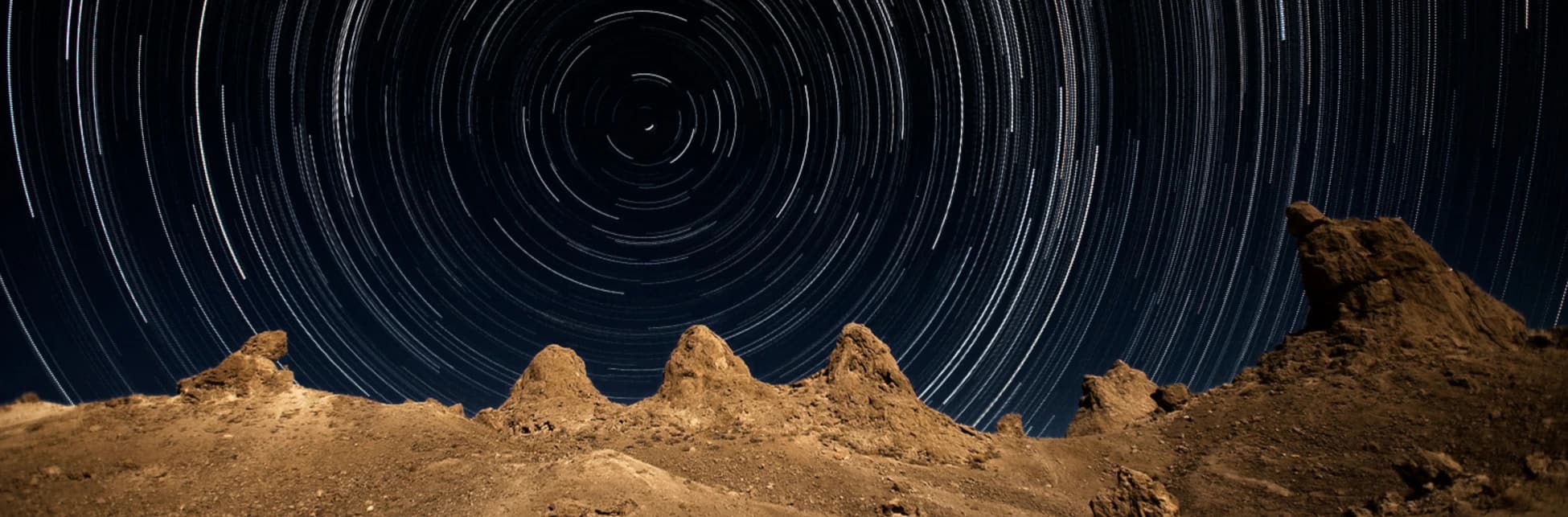 Ilustración. Un fondo oscuro con trazos circulares que representan el movimiento de las estrellas en el cielo nocturno.