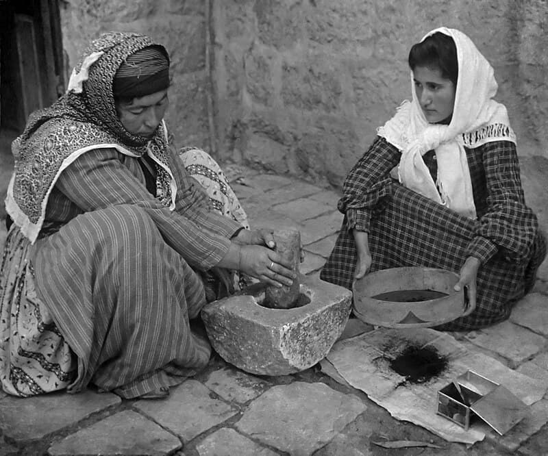 Fotografía. Dos mujeres árabes muelen café en cuclillas.