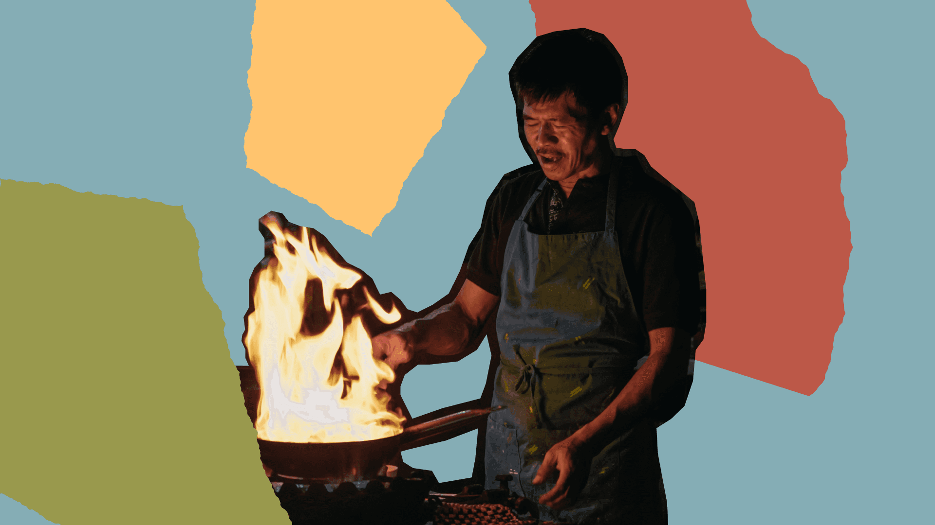 Fotografía. En el centro de la imagen un plano americano de un hombre de delantal que está cocinando. Delante suyo hay una paila de la que salen llamas.