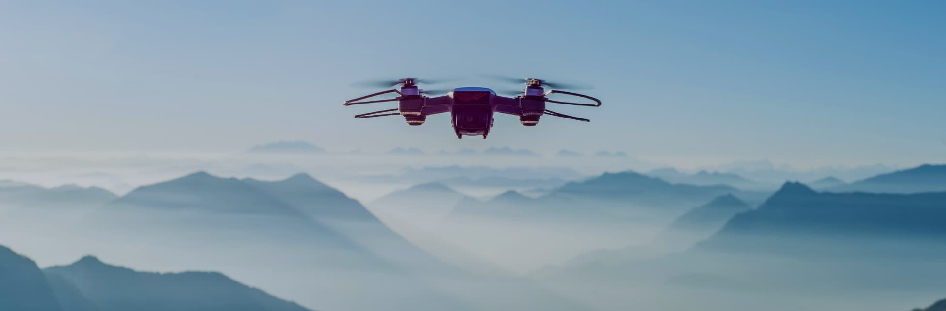 Fotografía. Un dron se eleva en el cielo, sobre unas montañas cubiertas de nieve.