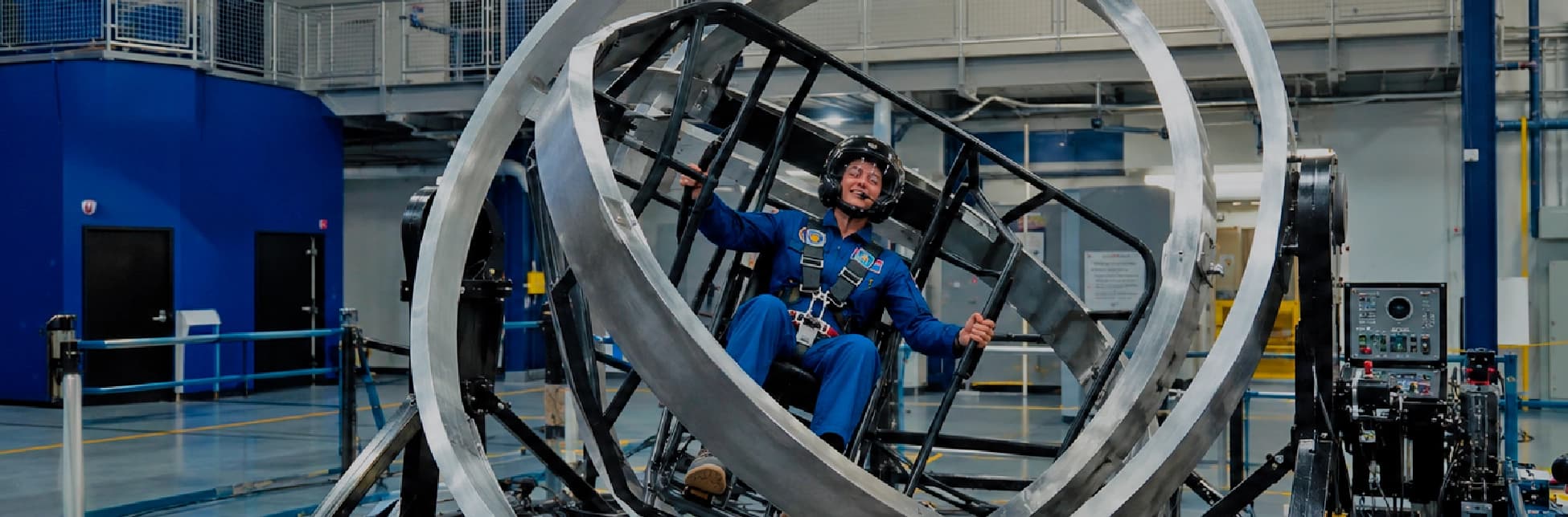 Fotografía de una persona dentro de un simulador circular metálico en un espacio industrial.