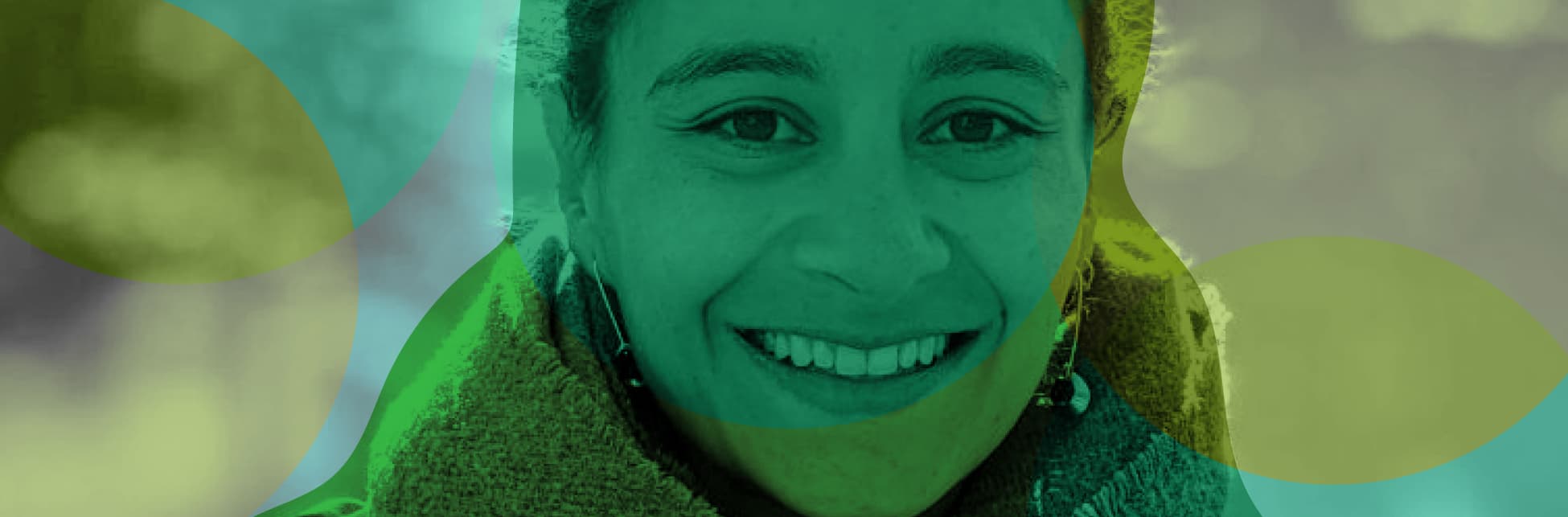 Foto horizontal. En el centro de la imagen una mujer de medio cuerpo, de frente, tiene una sonrisa en su rostro y mira fijamente a quien observa la imagen.