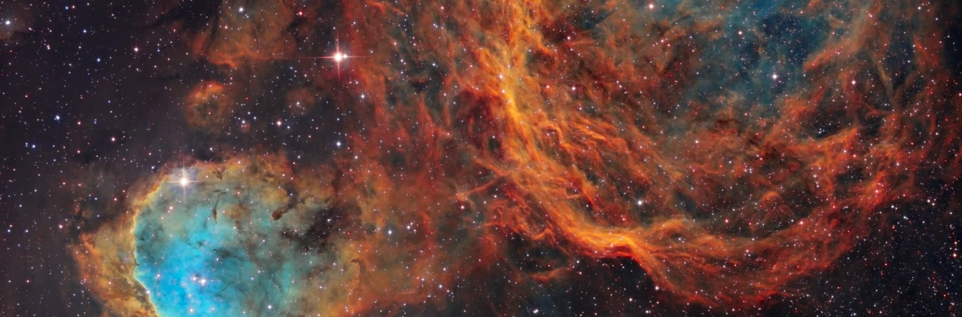 Fotografía de telescopio. Muchos puntos brillantes y formas polvorientas de colores rojo, narnaja y turquesa.