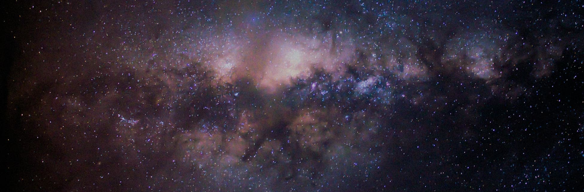 Ilustración. El fondo está compuesto por una fotografía del cielo nocturno donde se aprecia la Vía Láctea en tonos morados, azules y blancos.
