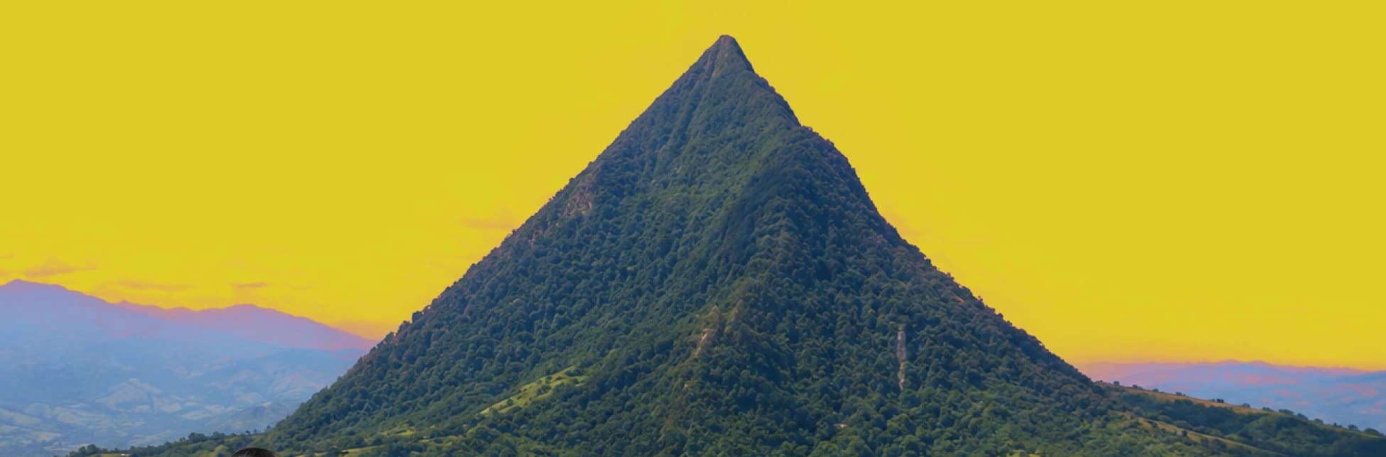 Fotografía de un paisaje montañoso con una gran colina cubierta de vegetación.