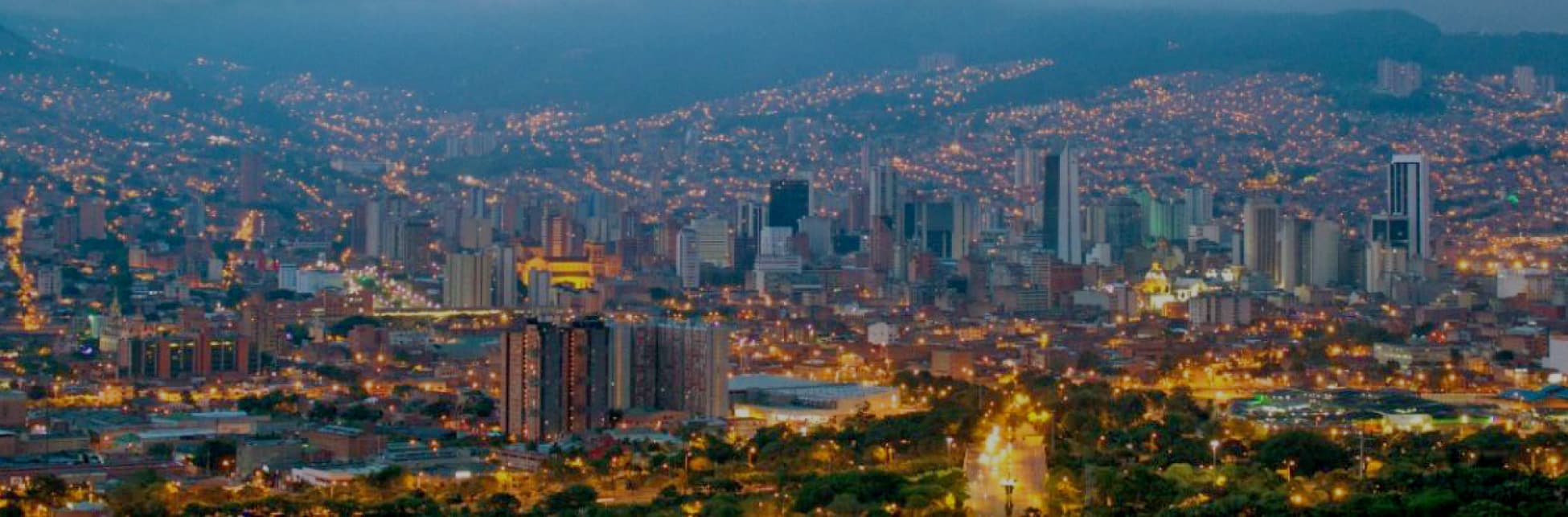 Fotografía. Una vista panorámica de la ciudad de Medellín, al fondo las montañas azuladas y más cerca se ven edificios y construcciones en el centro y la ladera.