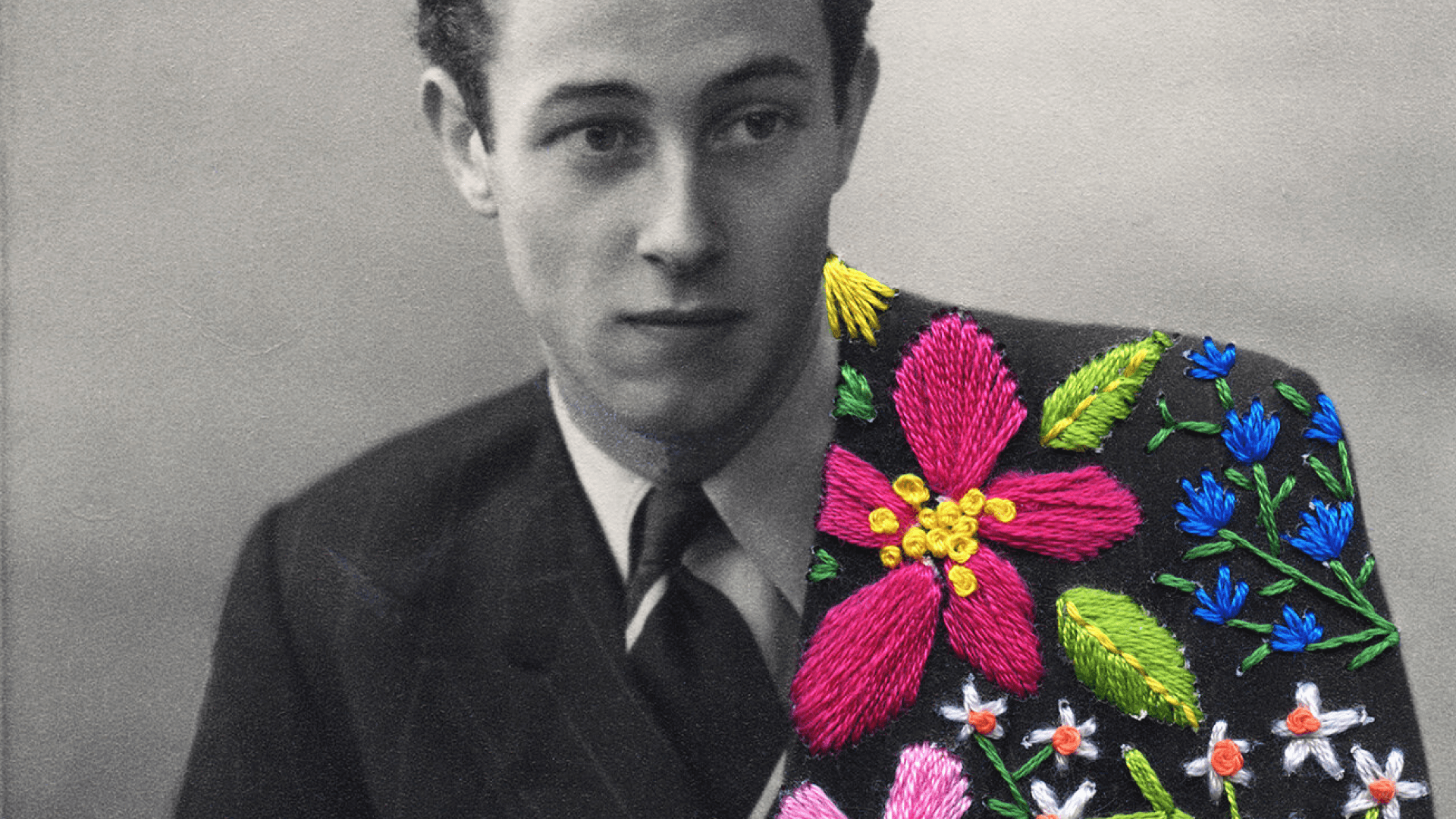 Fotografía. En el centro el primer plano de un hombre elegante. Su mirada se dirige hacia la derecha de la imagen. Tiene cachaco y corbata. La parte izquierda de su saco está bordada con flores y hojas de diferentes formas y colores.