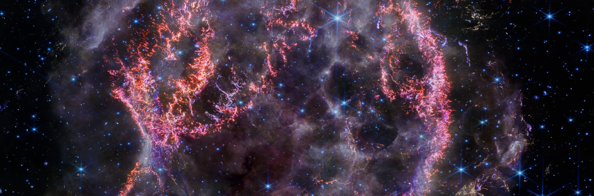 Afiche. En el fondo se observa una imagen astronómica que muestra un conjunto de gases y polvo interestelar en tonos morados, rosados y anaranjados sobre un cielo oscuro lleno de estrellas.
